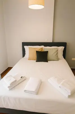 a large white bed with two white towels on it at Neos Kosmos Cozy Retreat - Central Comfort in Athens