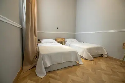 two beds in a room with wooden floors at Aerides V Suites in Athens