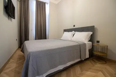 a bedroom with a bed with a gray blanket and a window at Aerides V Suites in Athens