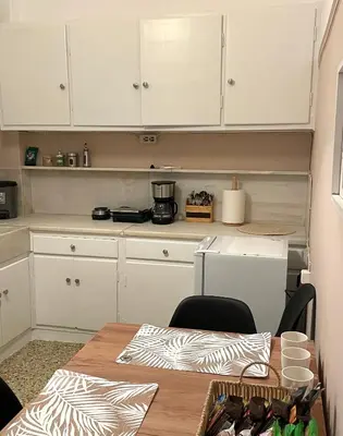 a kitchen with white cabinets and a wooden table at Spacious apartment near Panormou metro in Athens