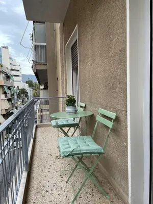 a green table and a chair on a balcony at Spacious apartment near Panormou metro in Athens