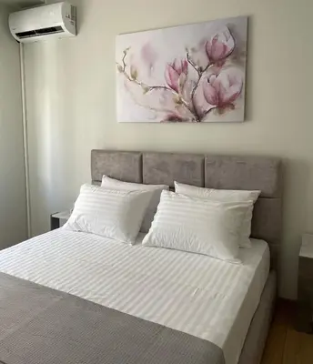 a bed with white sheets and a painting on the wall at Spacious apartment near Panormou metro in Athens