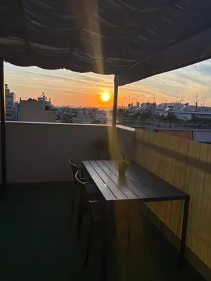 a wooden table on a balcony with the sunset at Athens penthouse with akropolis view! in Athens