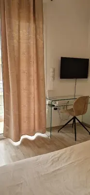 a bedroom with a desk and a television and a curtain at RolandApartaments in Athens