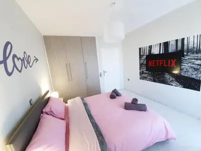 a bedroom with a pink bed and a sign on the wall at Panorama house near Teleperformance in Athens