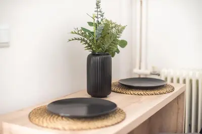a table with two black plates and a vase with a plant at Cozy Central Gem In Athens 2 min from metro in Athens