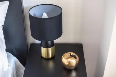 a black and gold lamp on a table next to a bed at Cozy Central Gem In Athens 2 min from metro in Athens