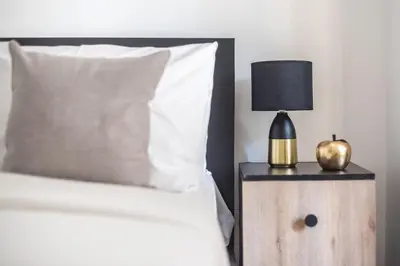 a bed with a black lamp on a wooden night stand at Cozy Central Gem In Athens 2 min from metro in Athens