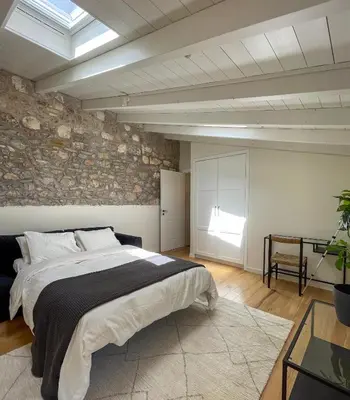 a bedroom with a large bed and a stone wall at Bigtrel Athens in Athens