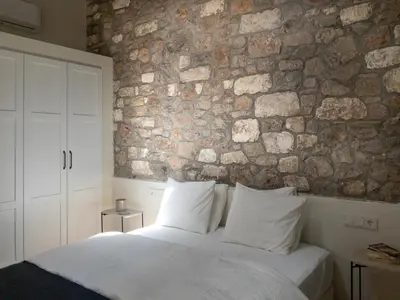 a bedroom with a stone wall and a bed with pillows at Bigtrel Athens in Athens