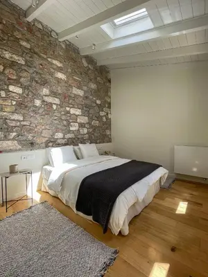 a bedroom with a large bed and a stone wall at Bigtrel Athens in Athens