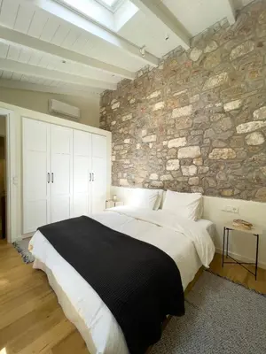 a bedroom with a large bed with a stone wall at Bigtrel Athens in Athens