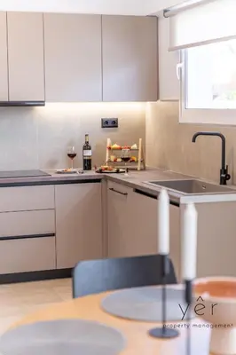 a kitchen with white cabinets and a table and a sink at Seaside Luxury - 3 Min to Freatida Beach in Piraeus