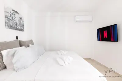 a white bed with two towels on top of it at Seaside Luxury - 3 Min to Freatida Beach in Piraeus