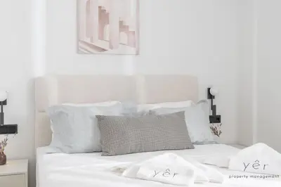 a white bed with white sheets and pillows at Seaside Luxury - 3 Min to Freatida Beach in Piraeus
