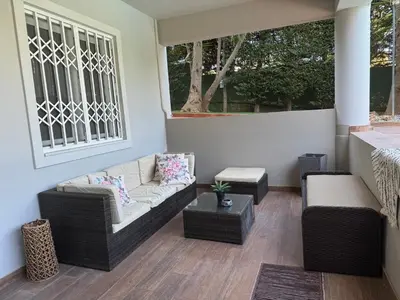 a porch with a couch and chairs and a window at Modern Apartment in Agia Marina Koropi in Aghia Marina