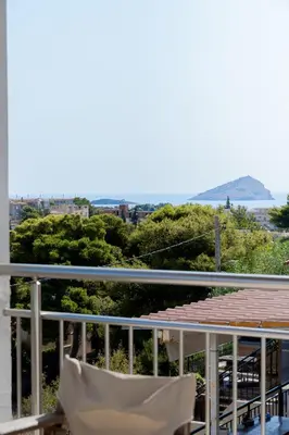 a chair on a balcony with a view of the city at Kalesma Hilltop Apartment by A&D Properties in Porto Rafti