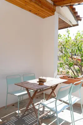 a wooden table and chairs on a patio at Kalesma Hilltop Apartment by A&D Properties in Porto Rafti