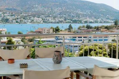 a table on a balcony with a view of the water at Kalesma Hilltop Apartment by A&D Properties in Porto Rafti