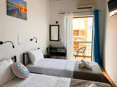 two beds in a room with a balcony at Hotel Liliana in Agia Marina Aegina