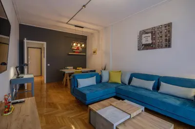 a living room with a blue couch and a table at KANARI street luxury living APT in Athens