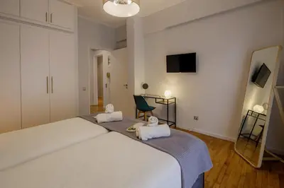 a bedroom with a large white bed and a chair at KANARI street luxury living APT in Athens