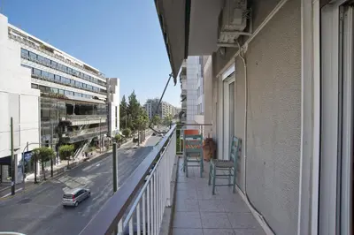 a balcony of a building with chairs and a street at Baroness Apt Piraeus Ctr 3BR, 2BA, AC, Walk to sea in Piraeus