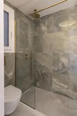 a bathroom with a glass shower with a toilet at Chrisostomou Square 14 Gold Apartment in Athens