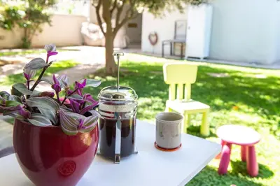 a table with a vase with flowers and a jar at The Holiday Place in Voula for 4 by Filos Inc in Athens