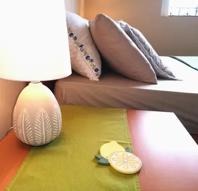 a lamp on a table next to a bed with pillows at Country House in Anavyssos in Anavissos