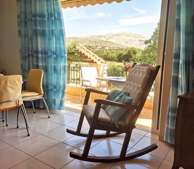 a rocking chair in a living room with a view at Country House in Anavyssos in Anavissos