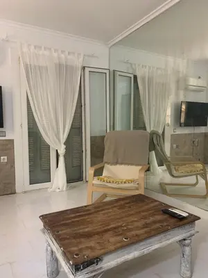 a living room with a table and a chair and windows at Dori's Seaside Apartment in Athens