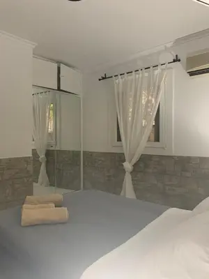 a white bedroom with a bed and a window at Dori's Seaside Apartment in Athens