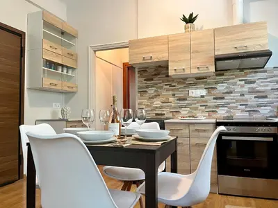 a kitchen with a table with white chairs and wine glasses at Voula Casita in Athens