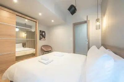 a bedroom with a large white bed and a mirror at Elegant Apartment in Athens