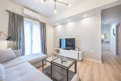 a living room with a white couch and a tv at Elegant Apartment in Athens