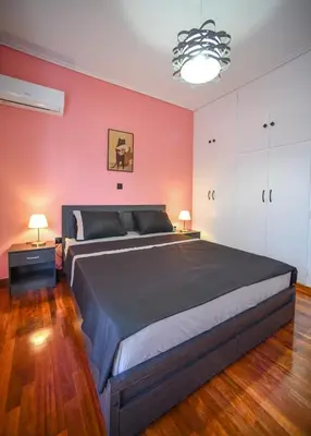 a bedroom with a large bed and a red wall at Spacious Apartment near Panormou Metro with Self Check-in in Athens