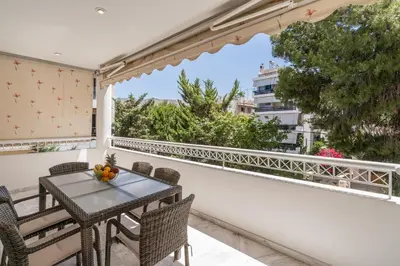 a balcony with a table and chairs and a window at Voula Riviera Luxury Apartment in Athens
