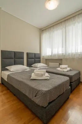 two beds in a bedroom with white towels on them at Voula Riviera Luxury Apartment in Athens