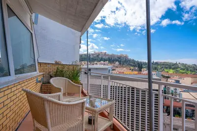 a balcony with two chairs and a table with a view at Urban loft with balcony across the Acropolis! in Athens