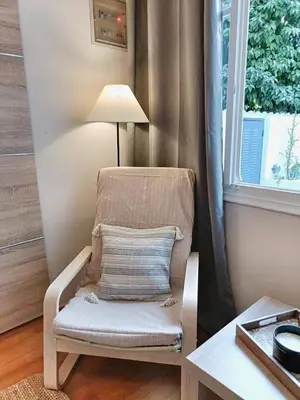 a chair with a pillow sitting next to a window at Harmony Apartment Near Metro Station in Athens