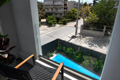 a balcony with a bench and a swimming pool at Emerald Stone Apartment Varkiza in Vari