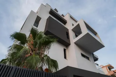 a white building with black windows and a palm tree at Emerald Stone Apartment Varkiza in Vari