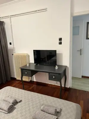 a living room with a black desk with a flat screen tv at Billy & Andrianna Villa Lagonisi in Kalívia Thorikoú