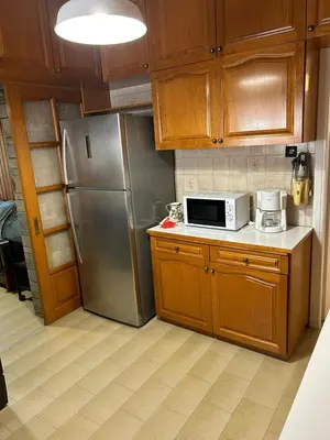 a kitchen with wooden cabinets and a stainless steel refrigerator at Billy & Andrianna Villa Lagonisi in Kalívia Thorikoú