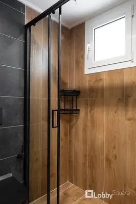 a shower with a glass door and a window at Aria Apartment in Athens