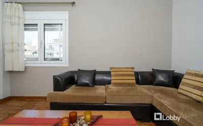 a living room with a brown couch and a table at Aria Apartment in Athens