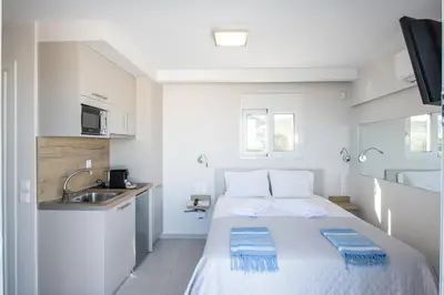 a small white room with a bed and a sink at RoofTop Sea View Cabin in Vari
