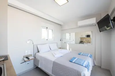 a white bedroom with a bed and a tv at RoofTop Sea View Cabin in Vari