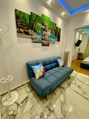 a living room with a blue couch and paintings on the wall at Soul spa suites in Athens